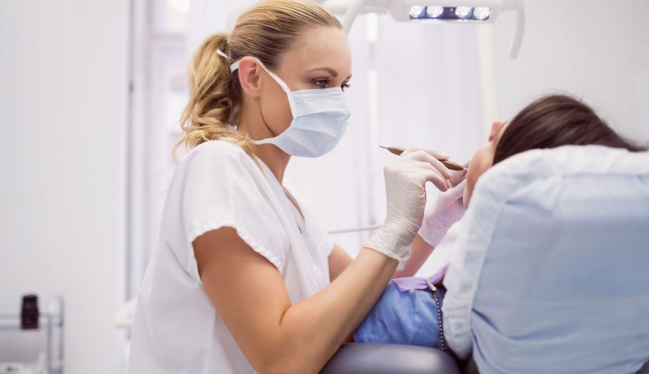 Zahnärztin führt ein Parodontologie-Behandlung bei einem Patienten in München Schwabing durch